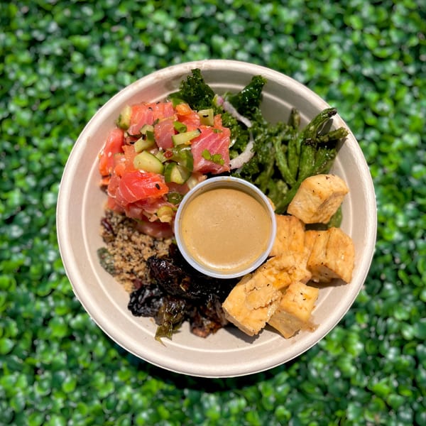 Fork 'N' Bowl poke bowl with salmon, tofu, kale, seaweed, and a side of sauce.